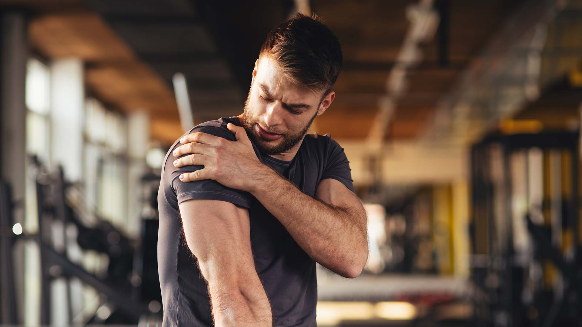 man-holding-sore-muscle-in-gym